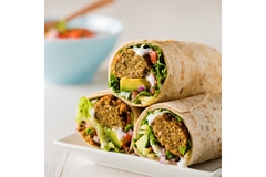Fresh falafel wraps with vegetables, avocado, and yogurt sauce on a white plate.